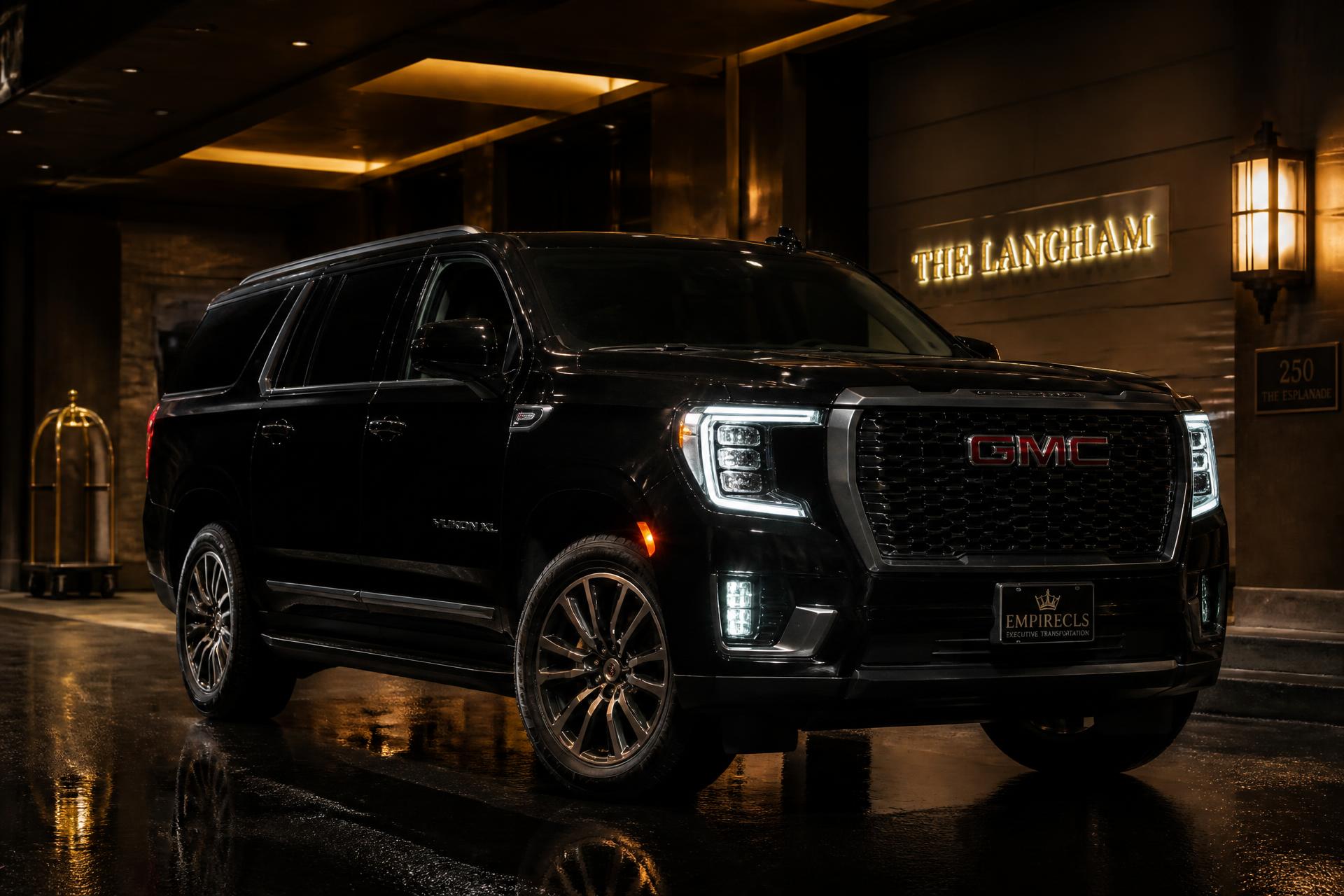 Black GMC Yukon XL waiting under a luxury hotel portico at night